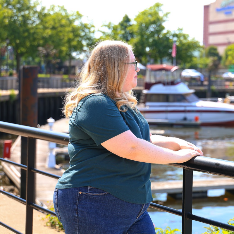 Katherine, a stroke survivor, standing by a waterfront railing, reflecting on her stroke recovery journey.